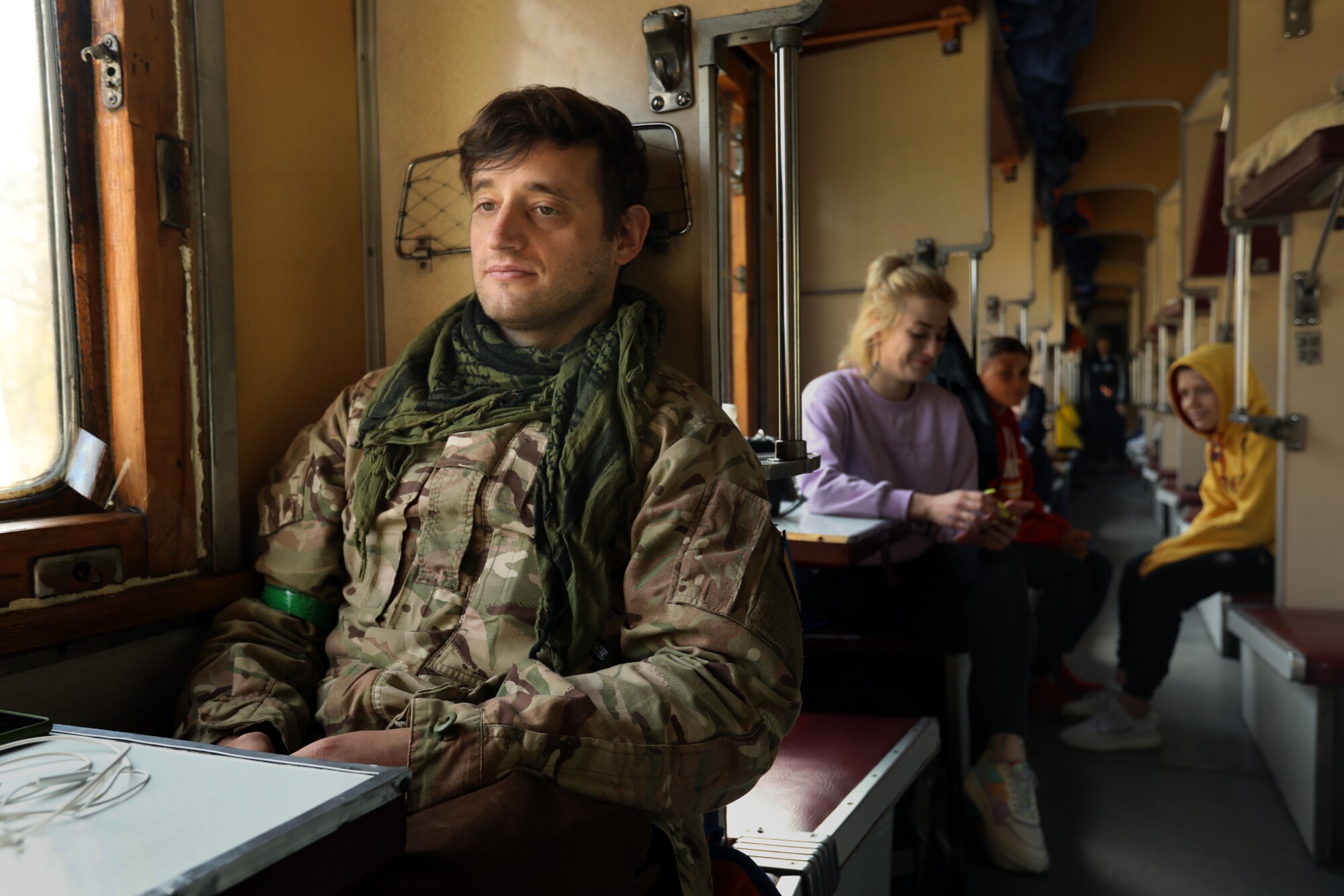 A man in fatigues is seated in front of a woman 