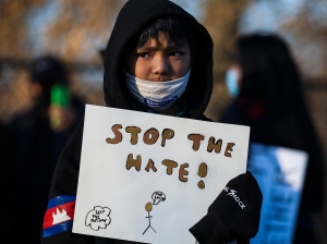 A boy holds a "stop the hate" sign